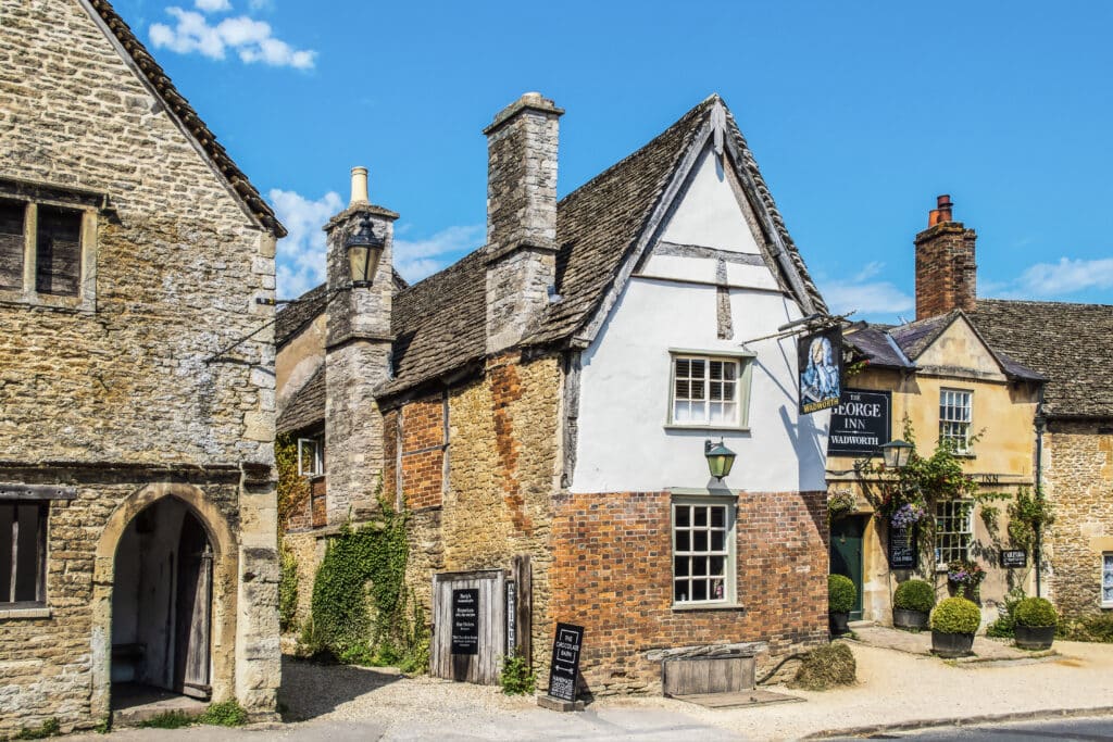 Lacock UK - Street scene and alley in Cotswold village of Lacock where scenes from Downton Abbey were shot - the George Inn- Wadworth