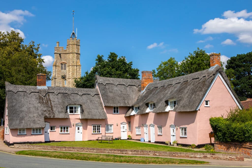 The picturesque view of St. Mary the Virgin church and the pink cottages in the village of Cavendish in Suffolk, UK