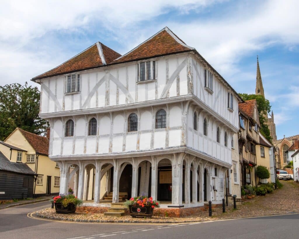 Essex, UK - September 6th 2021: A view of the historic Thaxted Guildhall, in the picturesque town of Thaxted in Essex, UK. The spire of Thaxted Parish Church is seen in the distance.
