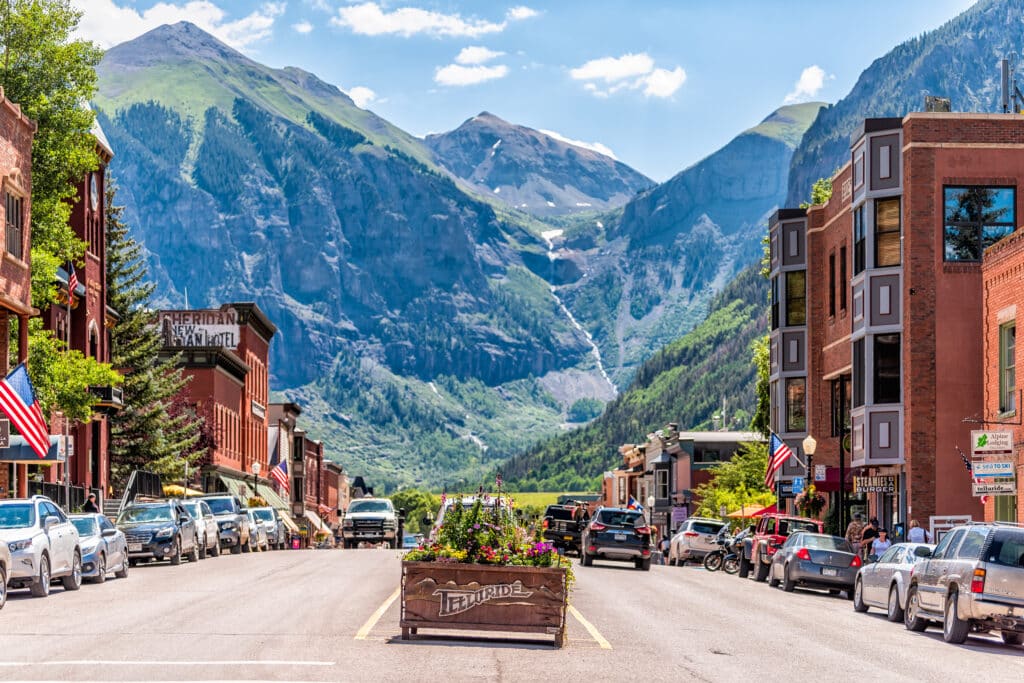 Telluride, USA: Small town village in Colorado with sign for city and flowers by historic architecture on main street mountain view