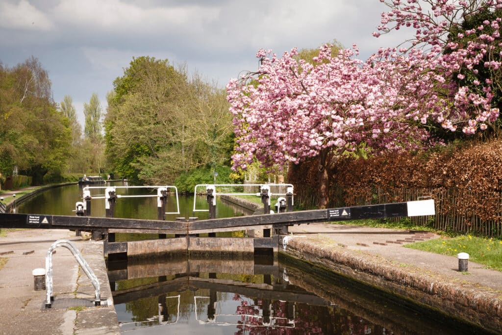 Canal lock with narrow boat on Grand Union Canal in London green belt countryside. Uxbridge, London, UK