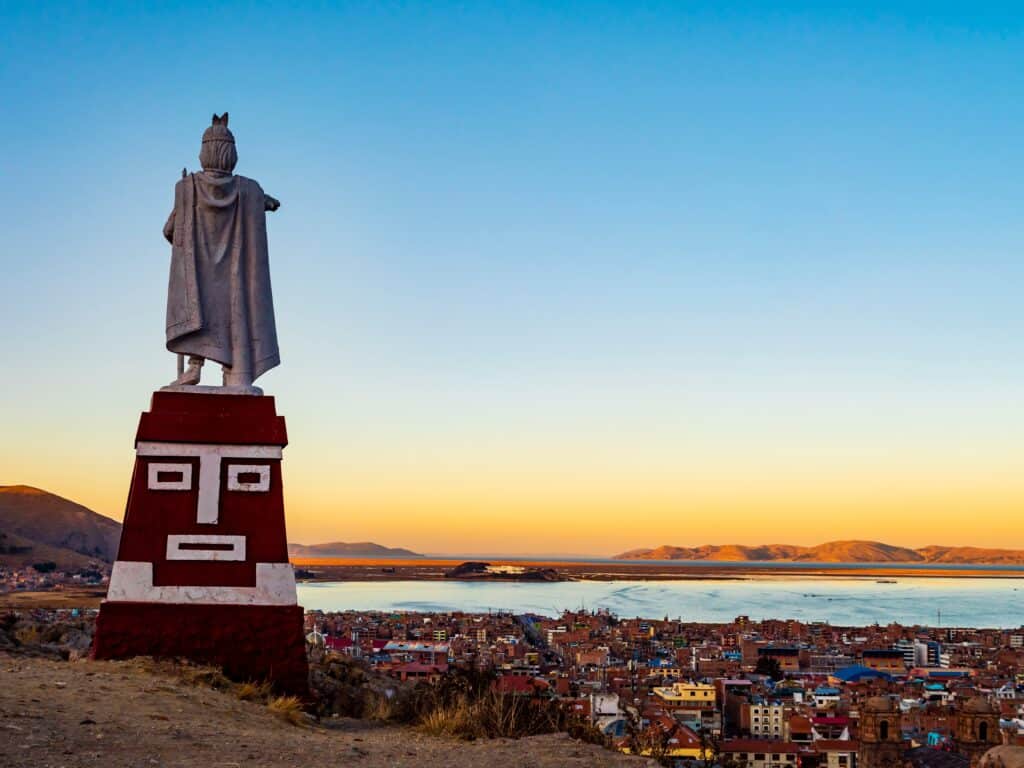 Puno, Peru: Stunning aerial view of lake Titicaca at sunset from Huajsapata Hill viewpoint with the monument to Manco Capac in foreground