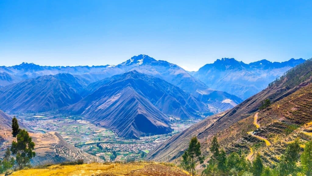 Breathtaking view of the Sacred Valley of the Incas in Peru, showcasing majestic Andean peaks, traditional villages, and stunning landscapes under a clear blue sky.