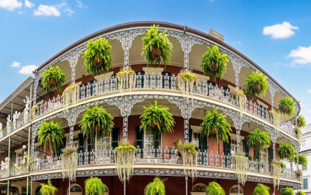 Wide angle view of hanging baskets on tradional New Orleans building in the French Quarter with grey wrought iron balconies
