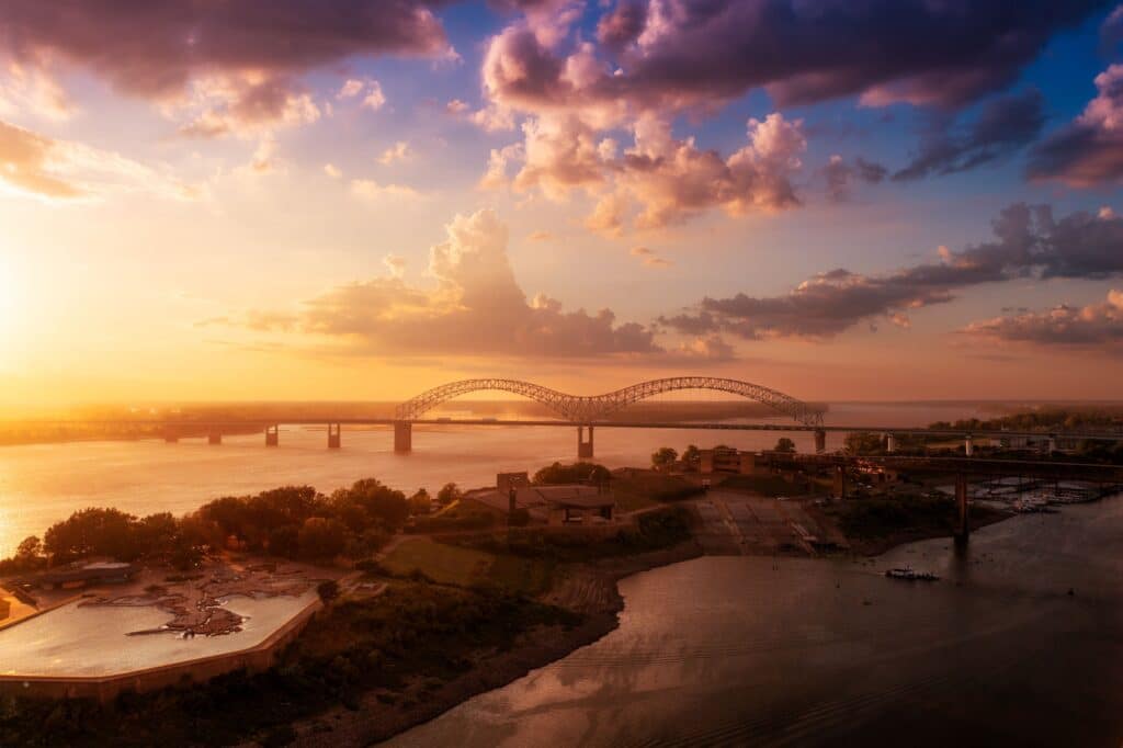A bird's eye view of Memphis Bridge connecting Tennessee and Arkansas at sunset over the Mississippi River