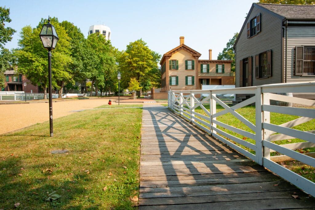 Wooden footpath leading along street with white fence and shadows in New Salem, Springfield, Illinois, USA.