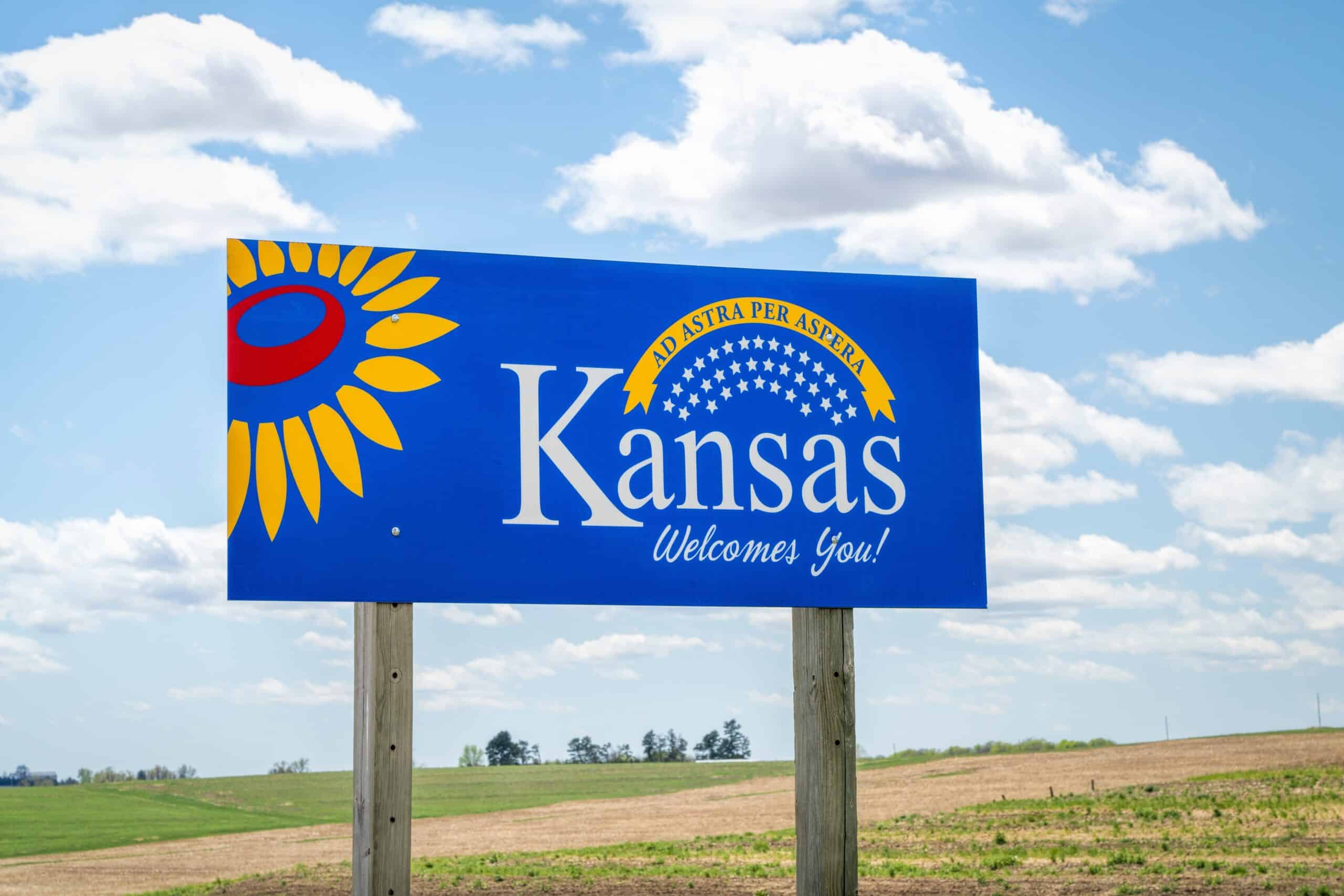 Kansas welcomes you - welcome roadside sign with a popular Latin phrase ad astra per aspera (through hardships to the stars), driving and travel concept