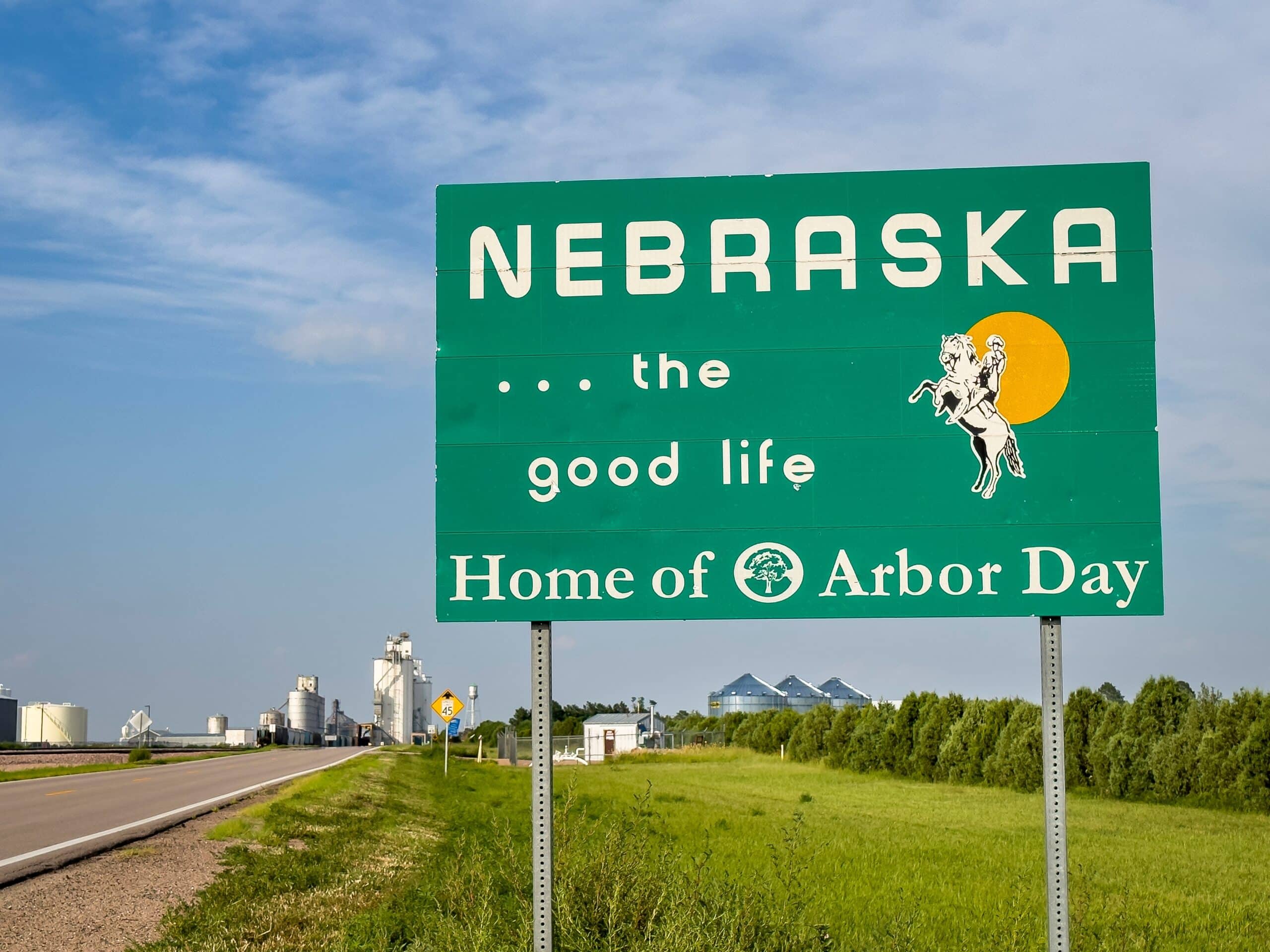 Nebraska, the good life, home of Arbor Day - roadside welcome sign at state border with Colorado, summer scenery with a rural town in background