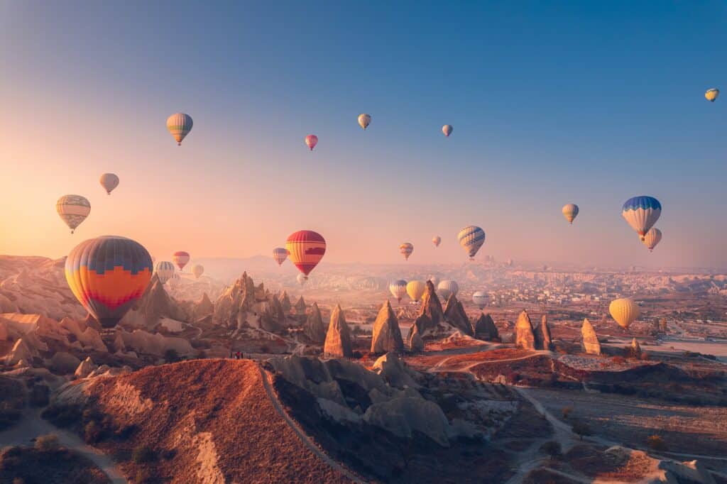 Amazing sunrise landscape in Cappadocia with colorful hot air balloon fly in sky over deep canyons, valleys. Turkey banner travel Concept.