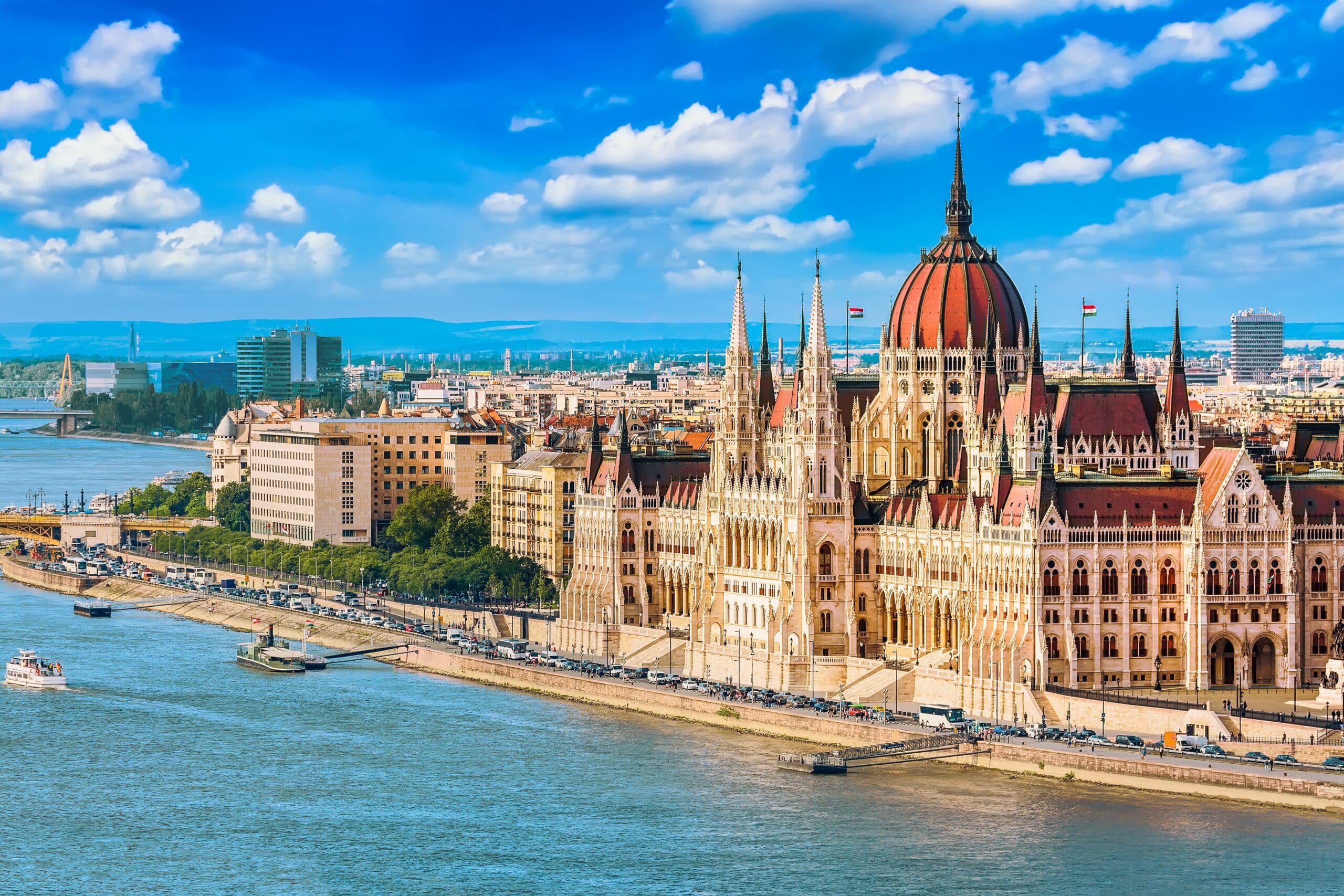 Parliament and Danube riverside in Budapest Hungary with sightseeing ship during summer sunny day with blue sky and clouds