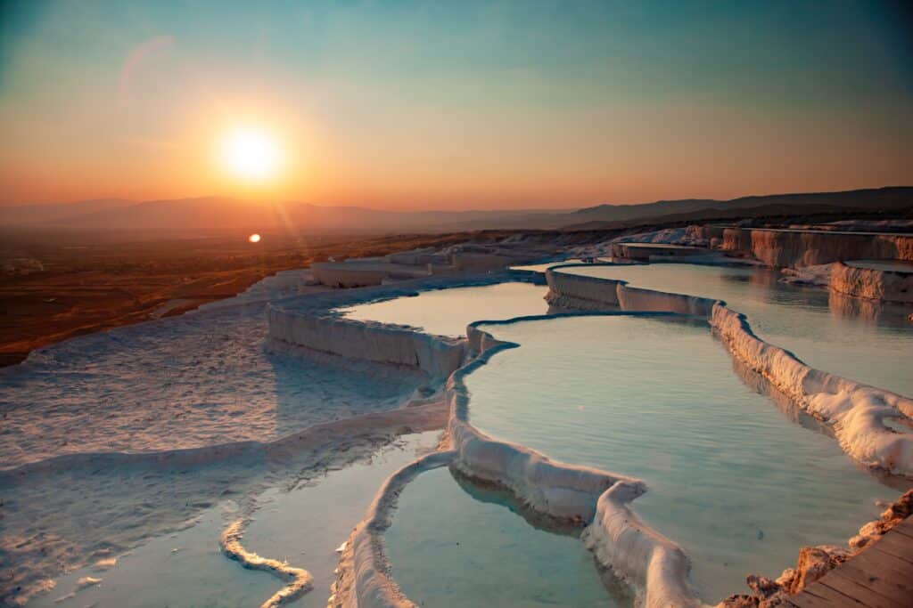 Captivating sunset over Pamukkale’s natural travertine terraces filled with turquoise thermal water.