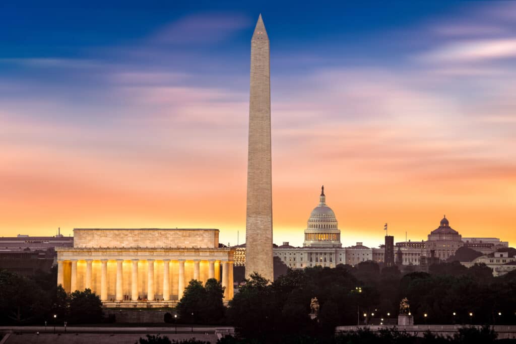 New dawn over Washington - with 3 iconic monuments illuminated at sunrise: Lincoln Memorial, Washington Monument and the Capitol Building.