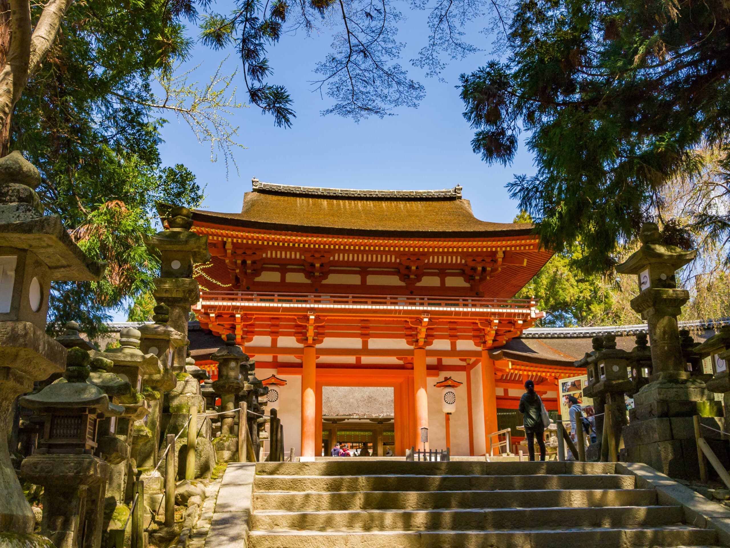 Entrance gate of Kasuga Taisha shrine in Nara surrounded by stone lanterns and forest