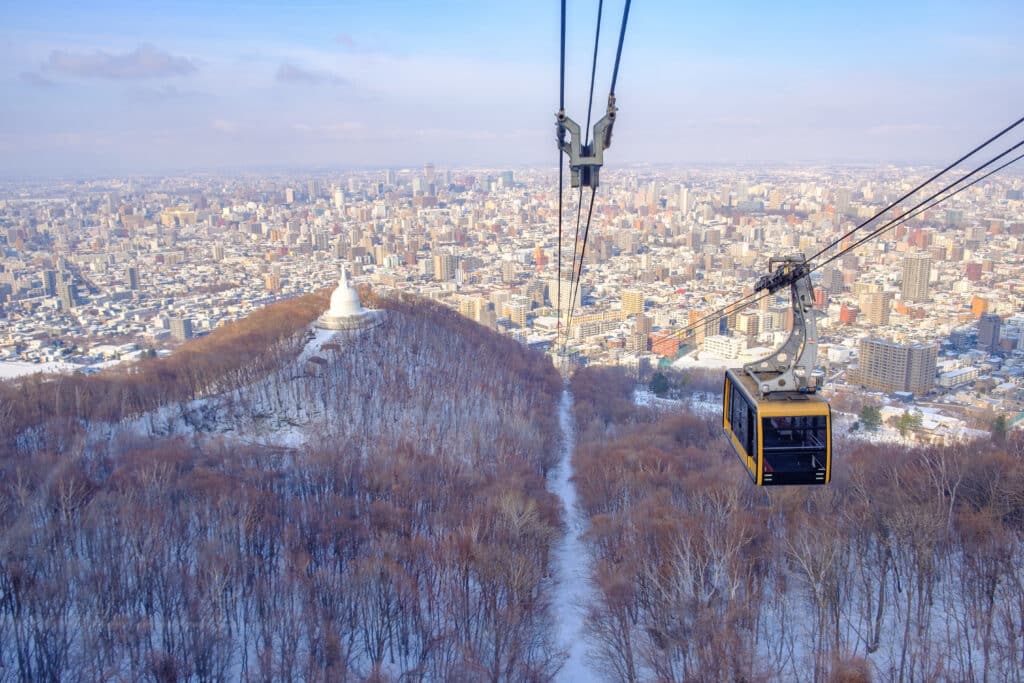 Mt. Moiwa Ropeway cabin ascending above snowy forests with views over Sapporo