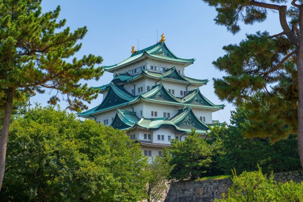 Nagoya Castle framed by trees with its distinctive green roofs and golden shachihoko ornaments