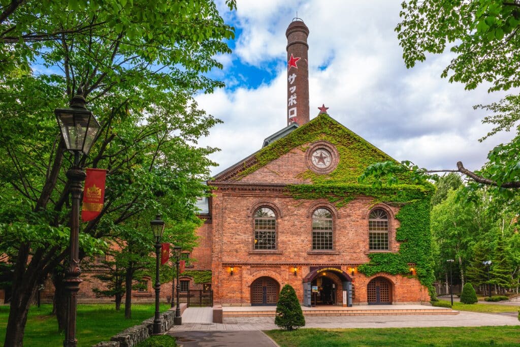 Historic red-brick Sapporo Beer Museum surrounded by trees and greenery