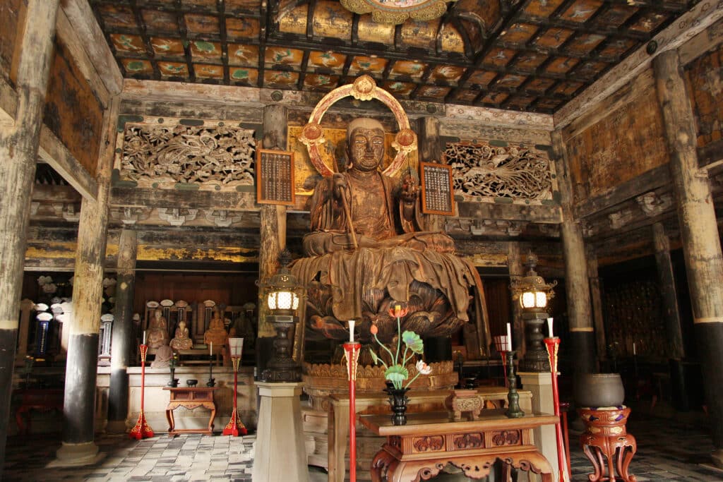 Large seated Buddhist statue inside a historic temple hall in Kamakura