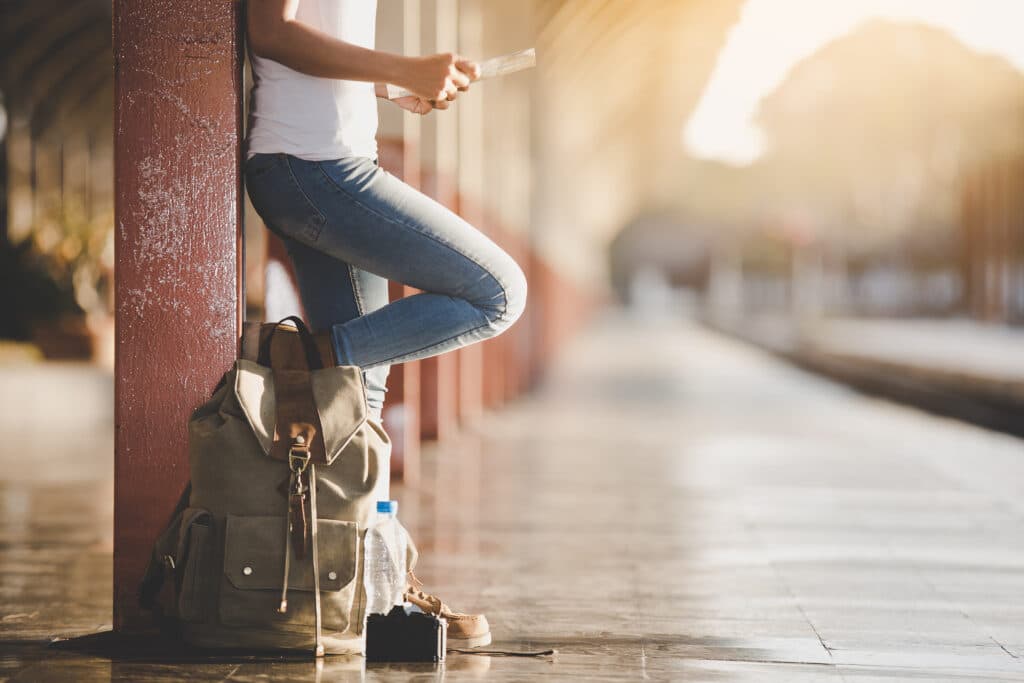 Traveler waiting at a train station with a small backpack