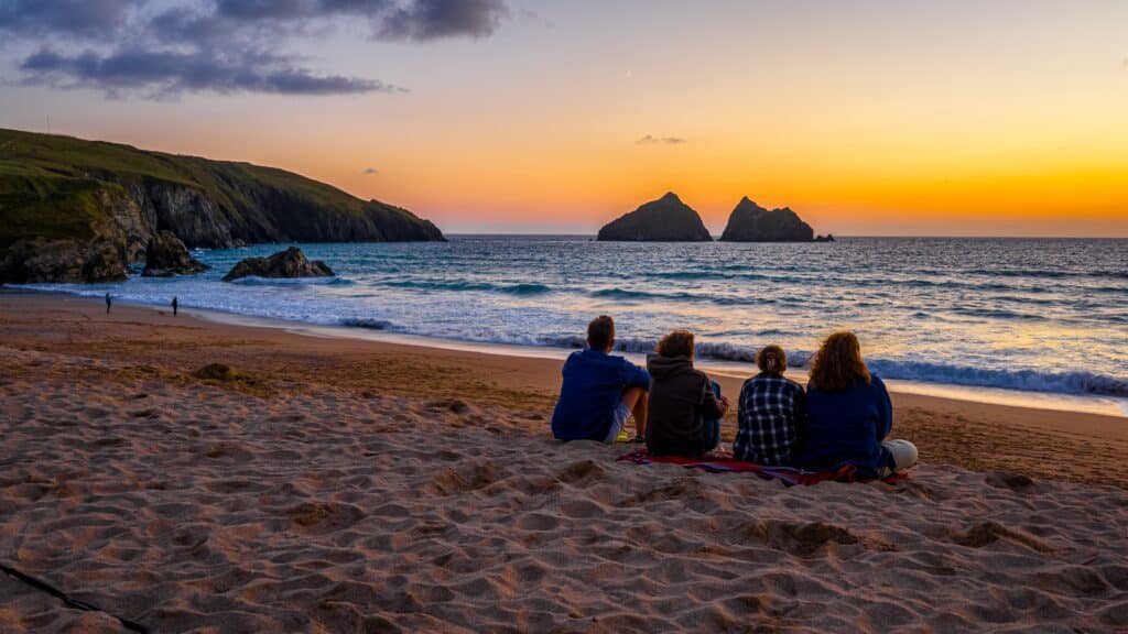 People watching the sunset from a sandy beach on the Cornwall coast