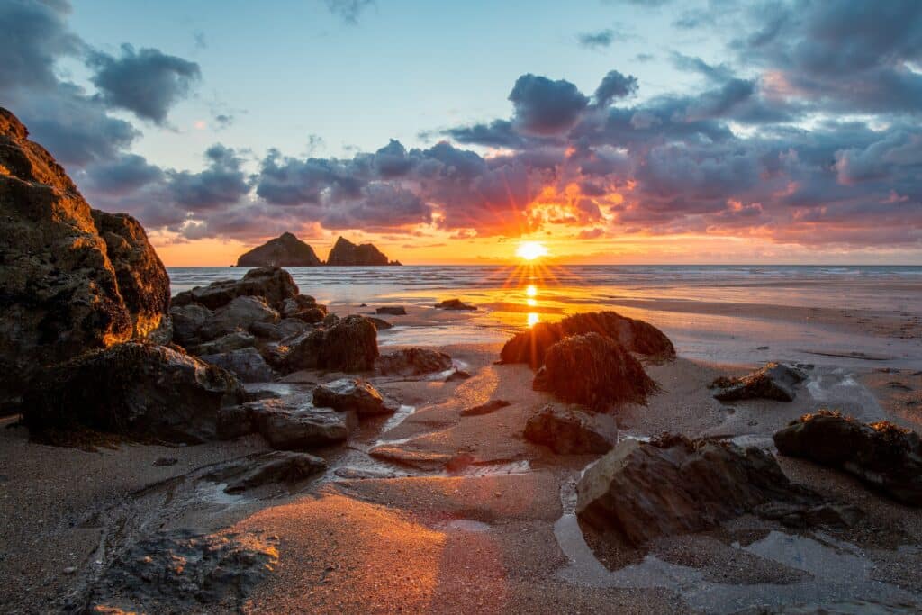Sunset over a sandy beach and rocky coastline in Cornwall, England