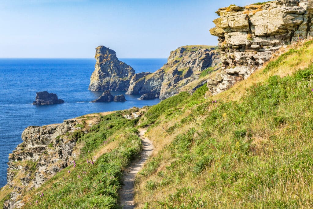 Coastal hiking trail overlooking rugged cliffs and blue sea in Cornwall