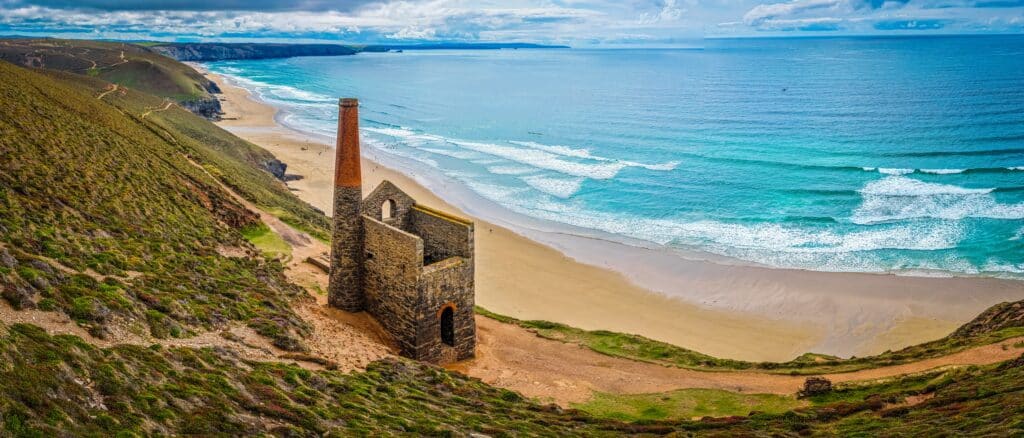 Historic tin mine ruins overlooking the coast and beach in Cornwall
